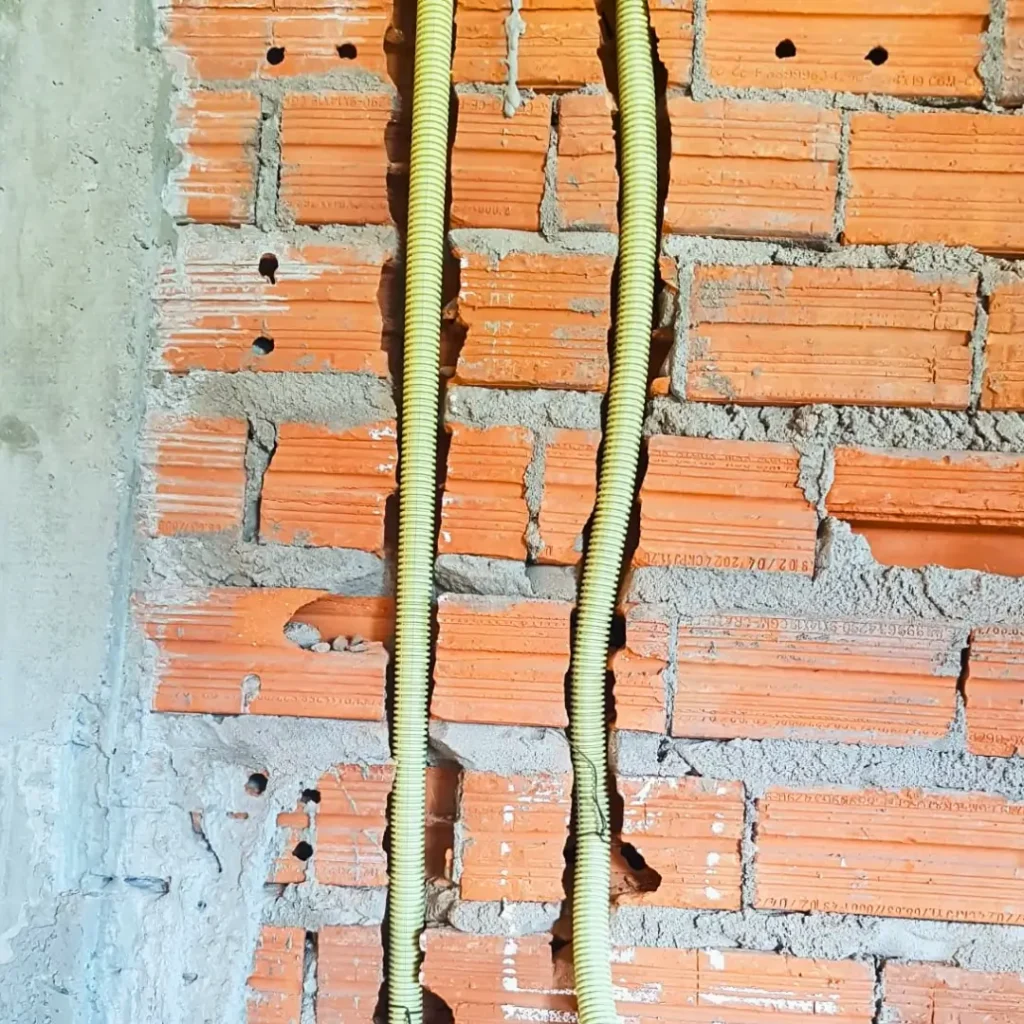 Foto mostrando o conduíte corrugado EcoRaio amarelo aplicado em uma obra feita por alvenaria.